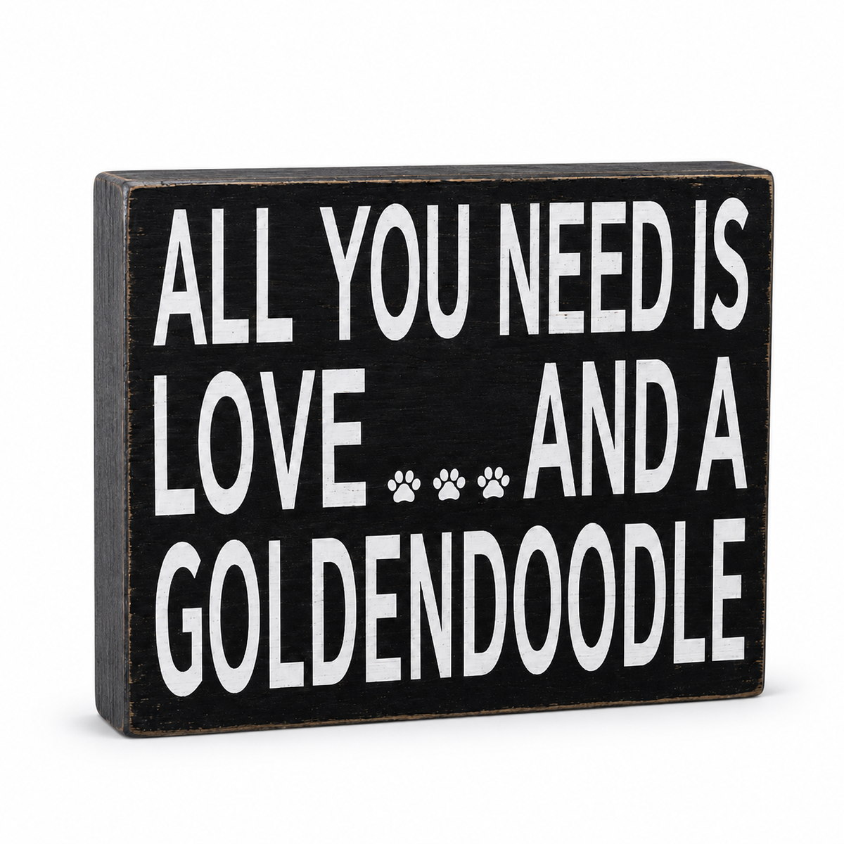 A rectangular black wooden sign with white text reading 'ALL YOU NEED IS LOVE.