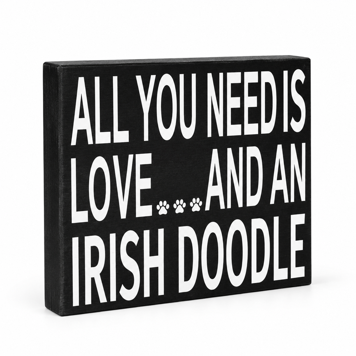 A rectangular black wooden sign with bold white text reading 'ALL YOU NEED IS LOVE.
