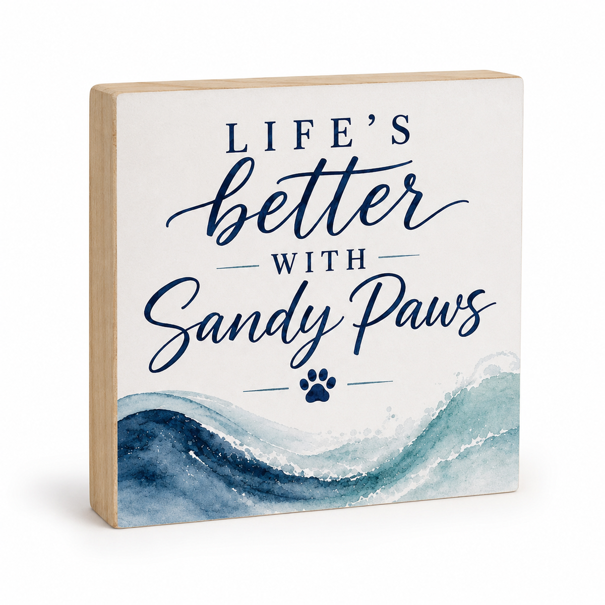 A square decorative wooden block sign with a light natural wood border, featuring the text 'LIFE'S better WITH Sandy Paws' in navy blue lettering over a white background, with a blue watercolor wave design at the bottom and a small paw print.