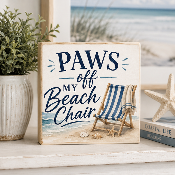 Decorative sign with 'PAWS off my Beach Chair' text on a shelf with beach-themed decor.