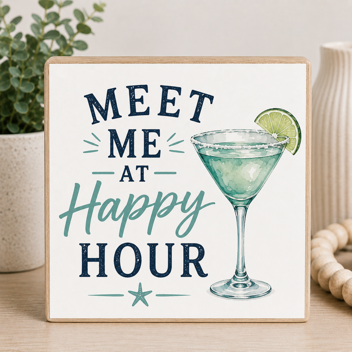 Decorative sign with a cocktail illustration and text 'Meet Me at Happy Hour' on a wooden surface.