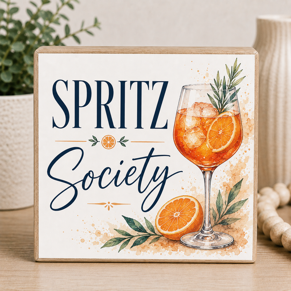 Decorative sign with 'Spritz Society' text, glass of spritz, and oranges on a light background.