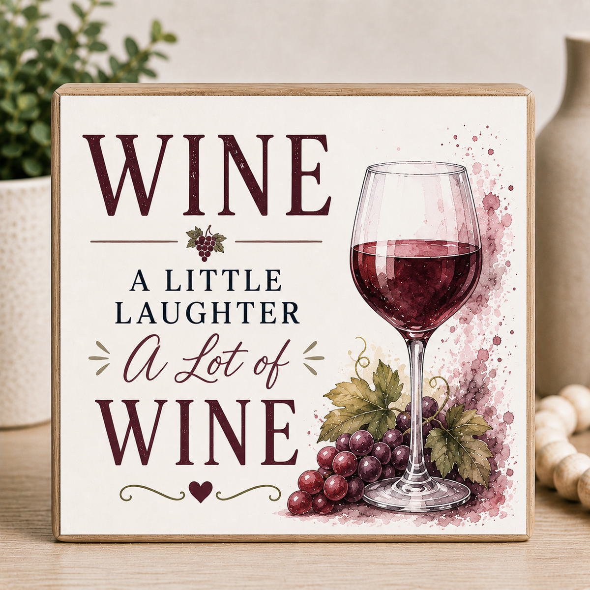 Decorative sign with a glass of wine and grapes, featuring text 'WINE a little laughter A Lot of WINE'.