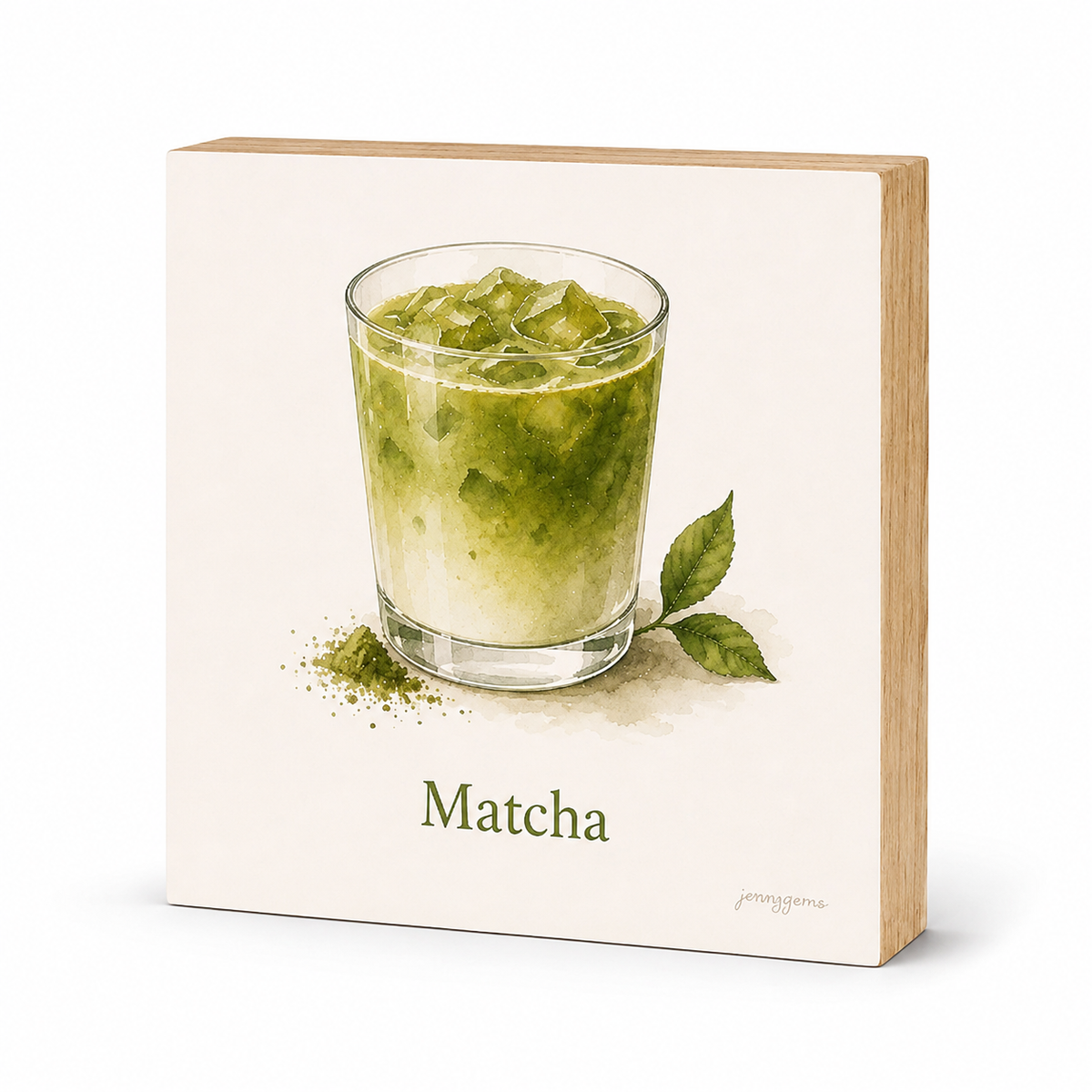 A square wooden block sign with a watercolor illustration of a matcha drink in a glass, green matcha powder, and two leaves, with the word 'Matcha' printed below. The sign has a cream face and natural light wood sides, shown on a white background.