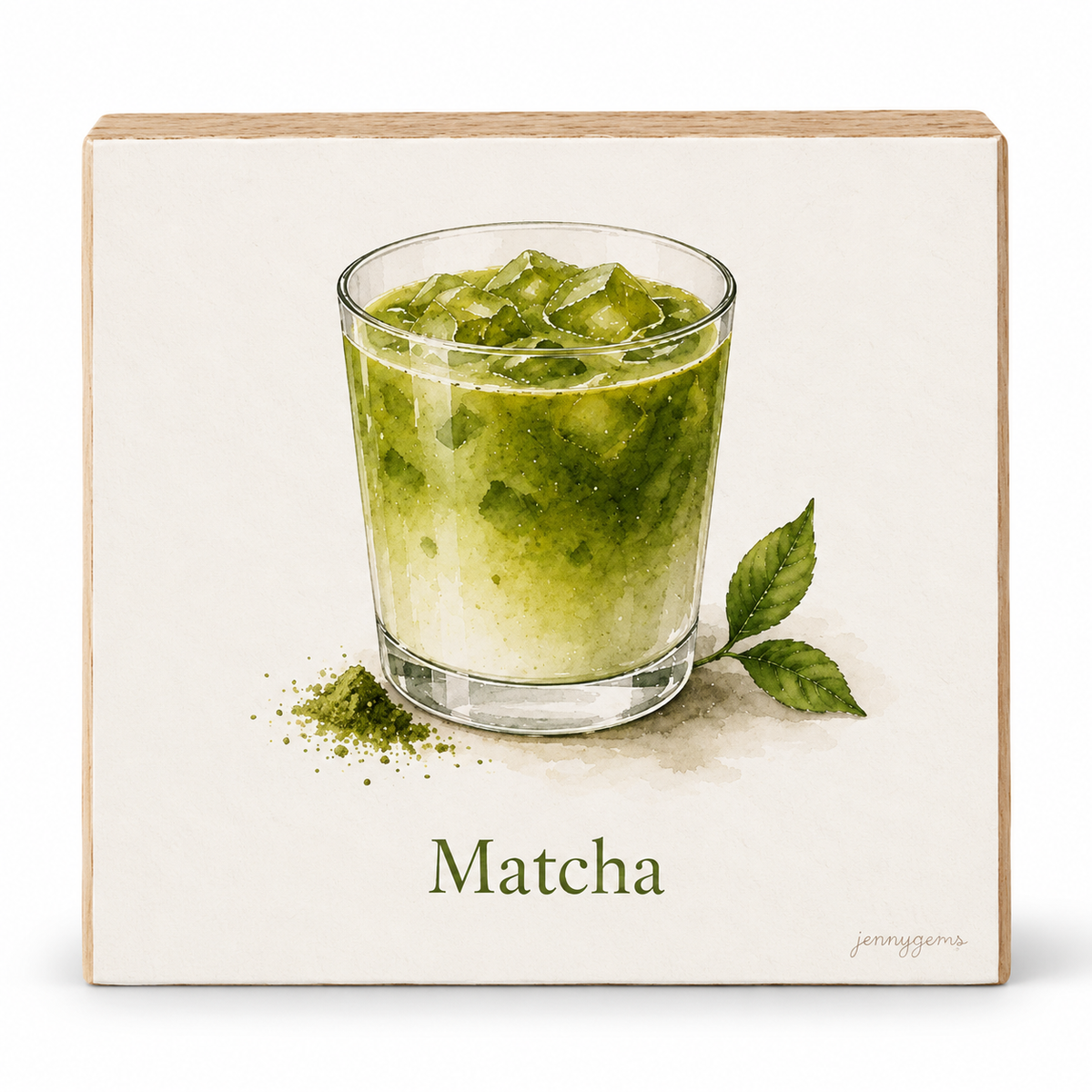 A square decorative wall sign with a light wood border and an off-white face, featuring a watercolor-style illustration of a matcha green drink in a clear glass with leaves and powder scattered below. The word "Matcha" is printed at the bottom, with a small artist signature in the lower right.