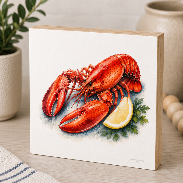 Painting of a red lobster with a lemon wedge on a white background, framed in wood.