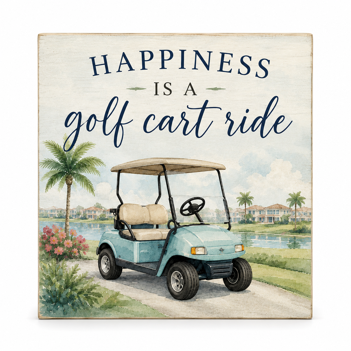 Square decorative sign with the phrase “HAPPINESS IS A golf cart ride” above a painted golf cart on a golf course path with palm trees, water, and houses in the background.