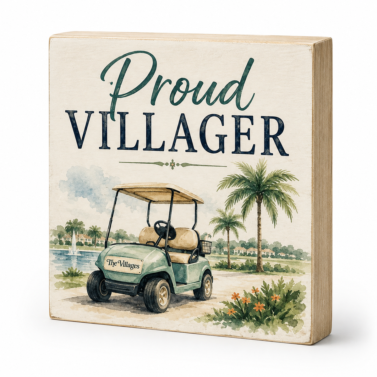 A square decorative wooden sign with a light natural wood frame and a printed tropical scene. The sign reads 'Proud VILLLAGER' in large lettering above an illustration of a golf cart, palm trees, water, and flowers.