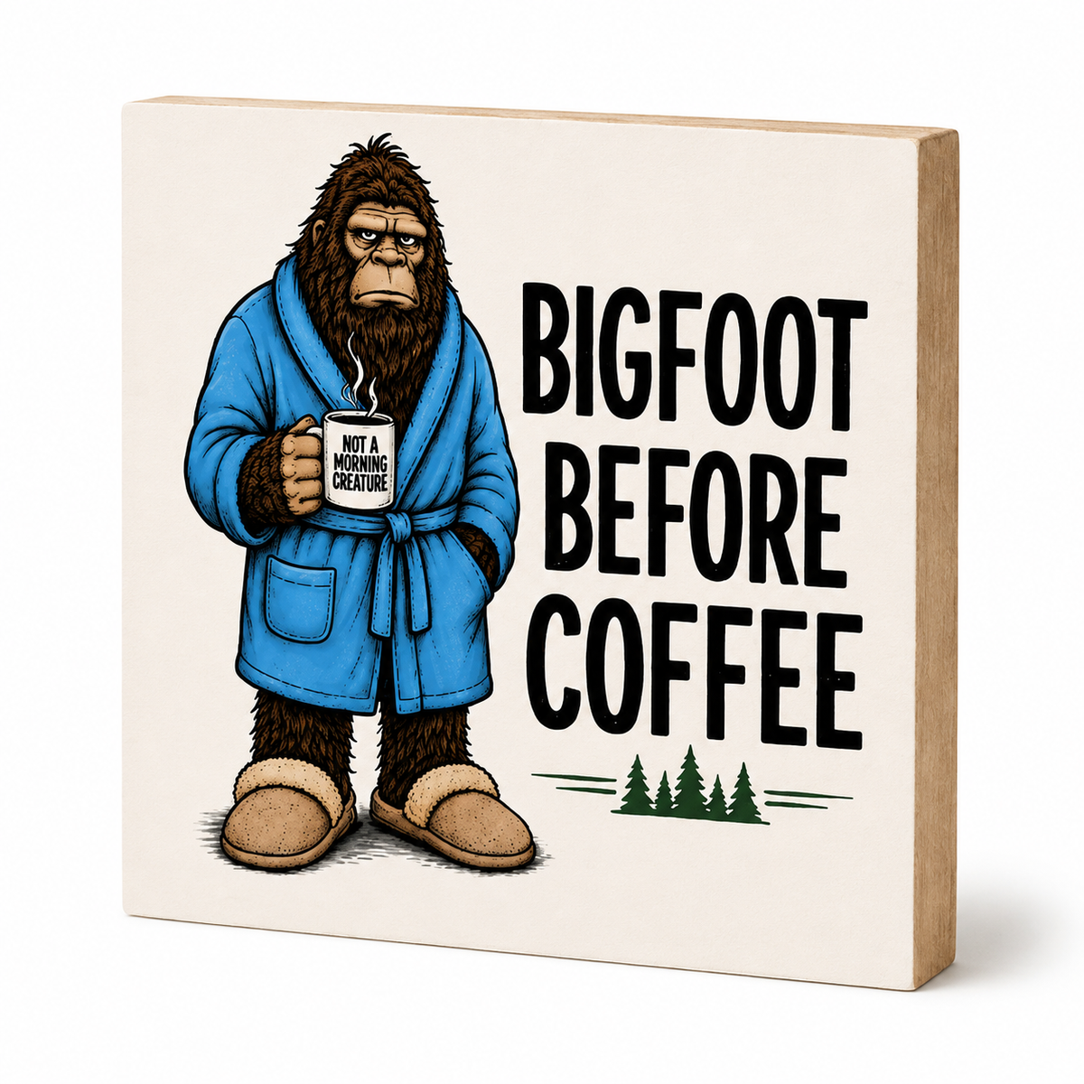 A square wooden block sign with a light beige face and natural wood sides, featuring an illustration of Bigfoot in a blue robe holding a coffee mug next to the text 'BIGFOOT BEFORE COFFEE' on a white background.