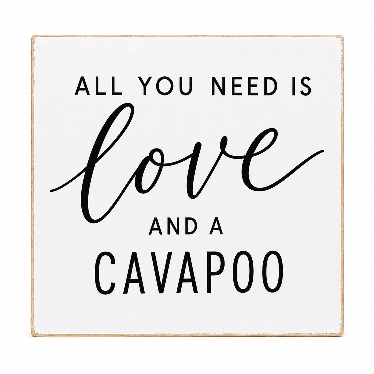 A square white decorative sign with a light natural wood border and black text that reads, 'ALL YOU NEED IS love AND A CAVAOO.'.