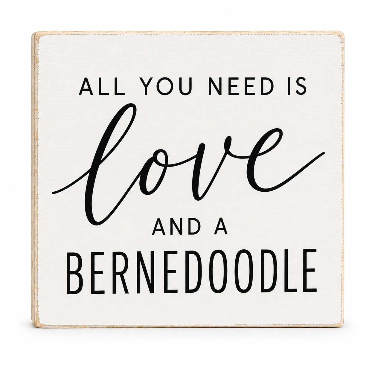 A square white decorative sign with a light natural wood border and black text that reads, 'ALL YOU NEED IS love AND A BERNEDOODLE' on a clean white background.