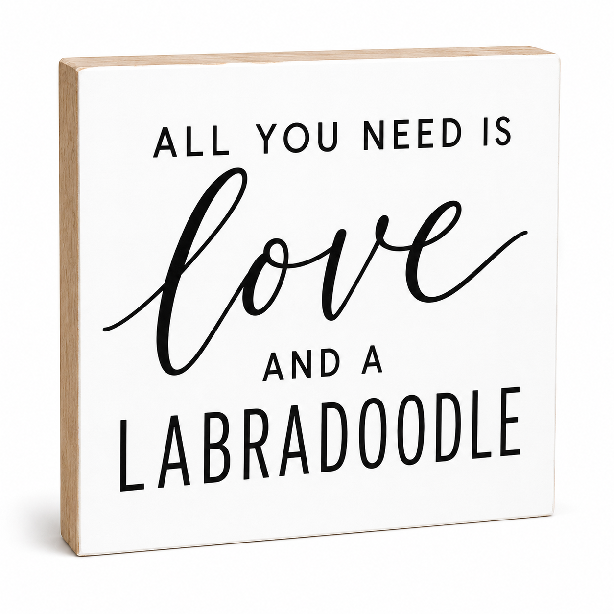 A square white decorative sign with a light natural wood edge, featuring the phrase 'ALL YOU NEED IS love AND A LABRADOODLE' in black lettering, shown on a clean white background.