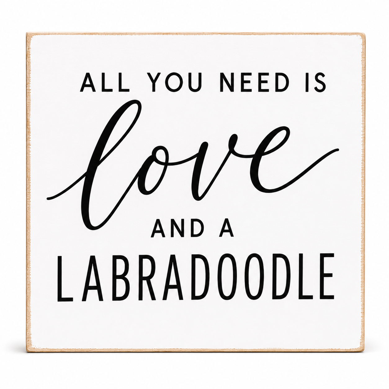 A square white decorative sign with a light natural wood border and black text that reads, 'ALL YOU NEED IS love AND A LABRADOODLE' on a clean white background.