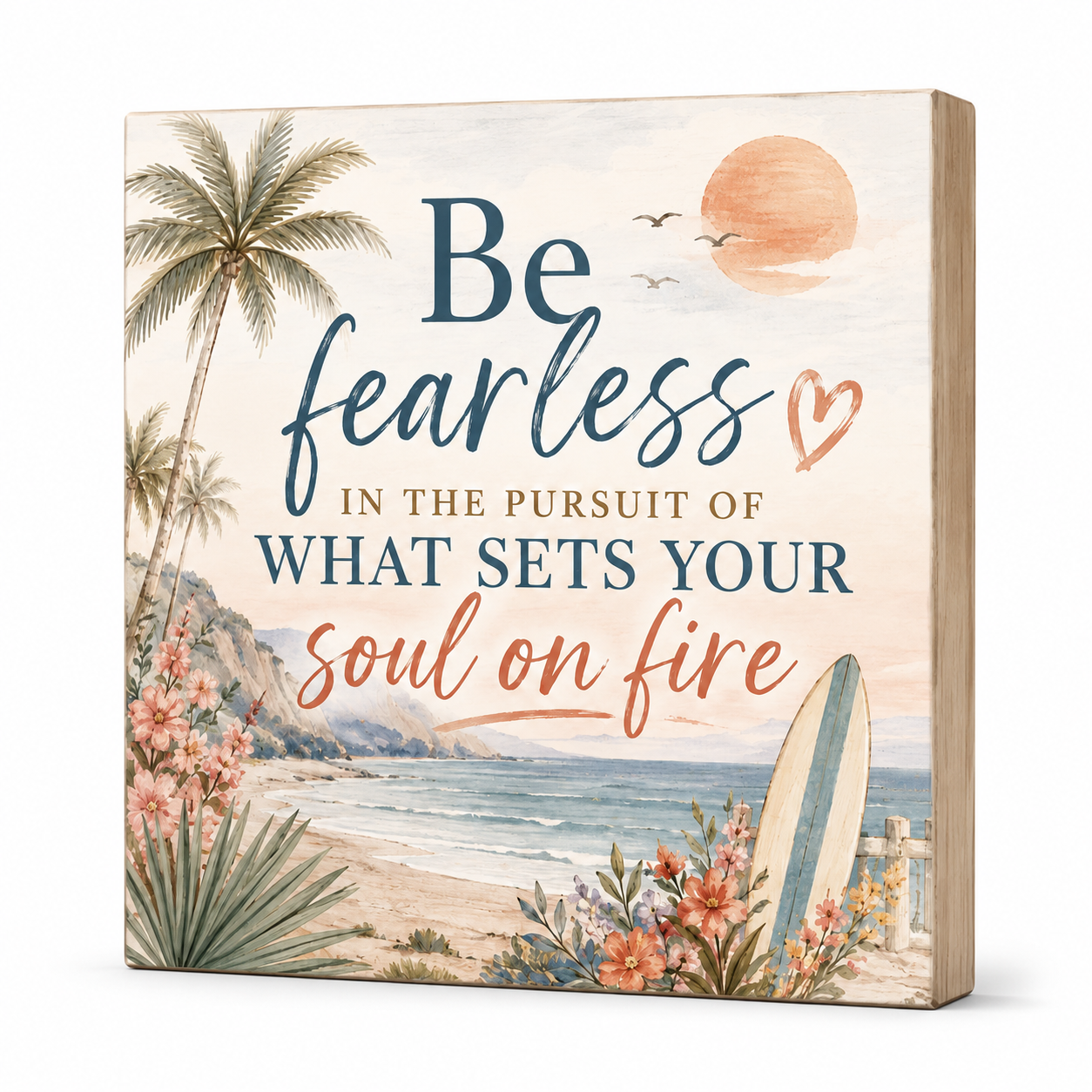 A square decorative wall sign with a beach scene printed on the front, featuring the phrase “Be fearless in the pursuit of what sets your soul on fire” in blue and coral lettering. The design includes palm trees, flowers, ocean water, a surfboard, and a peach sun, with a light wood side edge visible.