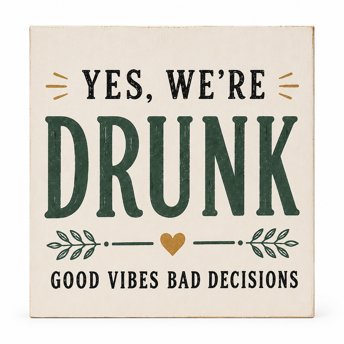 A square decorative sign with a distressed cream background and printed text reading “YES, WE’RE DRUNK” in dark green and black, with “GOOD VIBES BAD DECISIONS” below. A small gold heart and gold leaf accents are included.