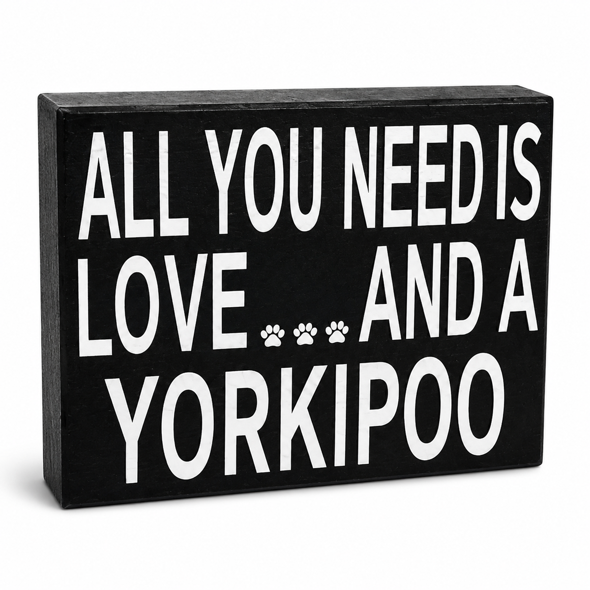 A rectangular black decorative sign with bold white text reading 'ALL YOU NEED IS LOVE.