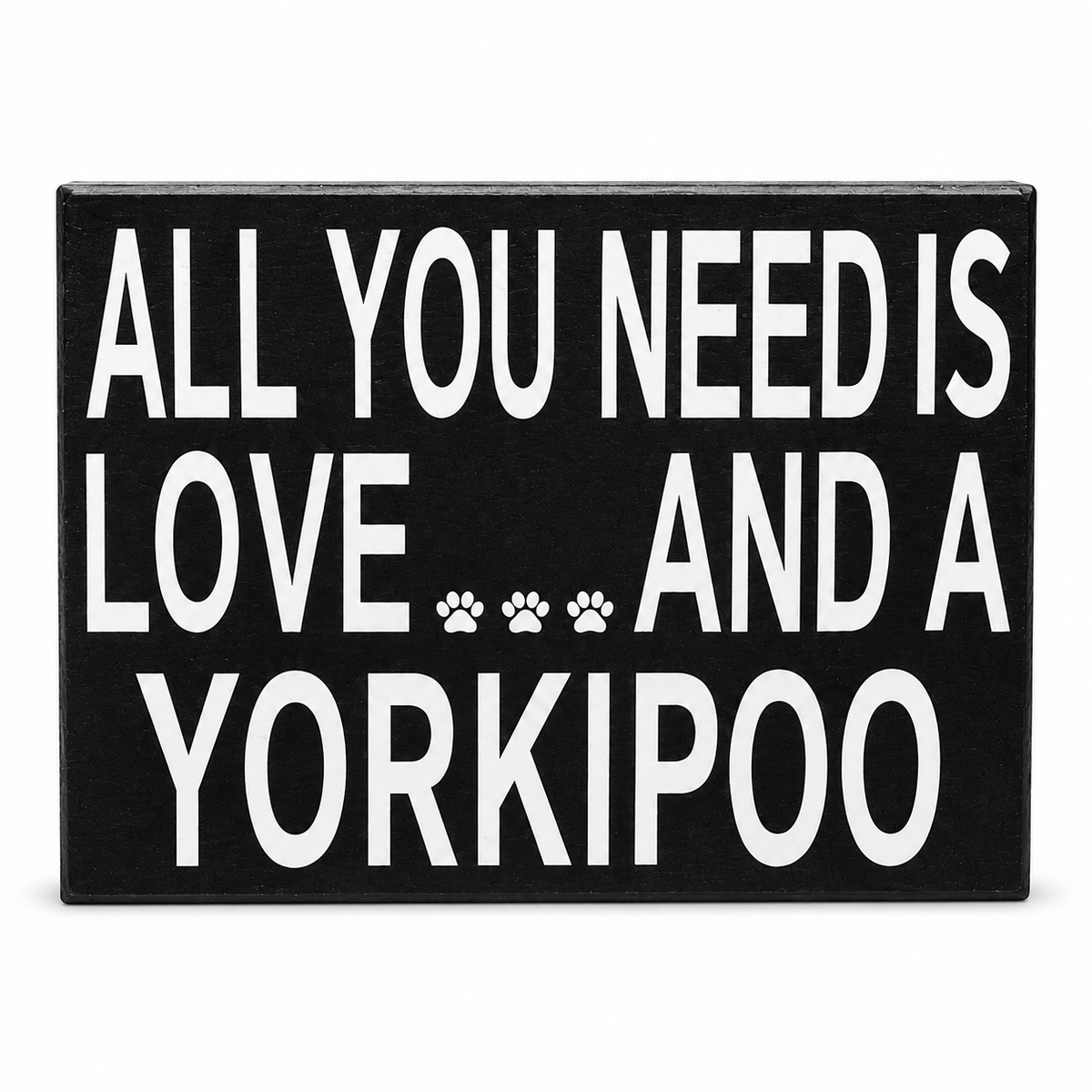 A rectangular black sign with bold white text reading 'ALL YOU NEED IS LOVE.