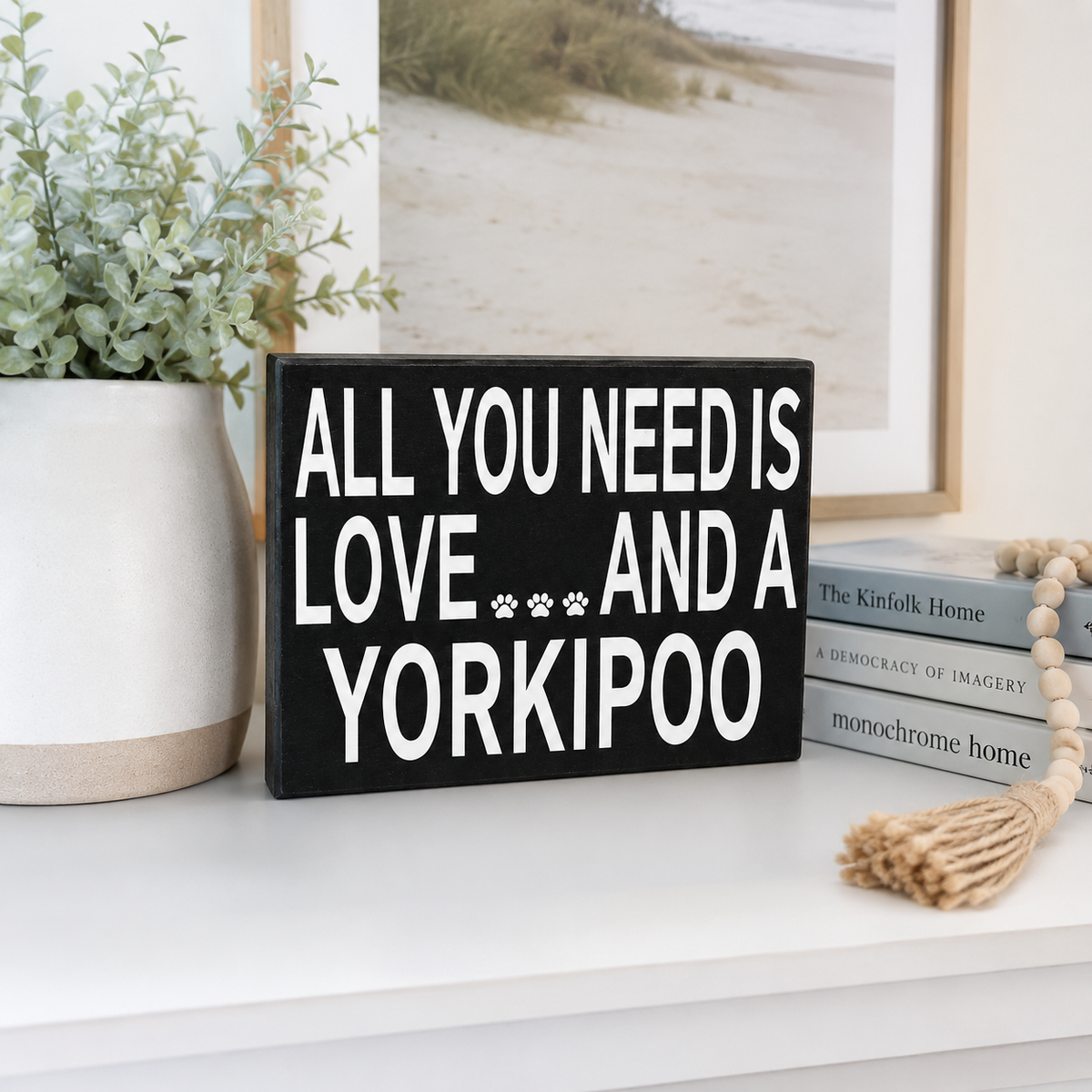 A black rectangular wooden sign with bold white text reading 'ALL YOU NEED IS LOVE.