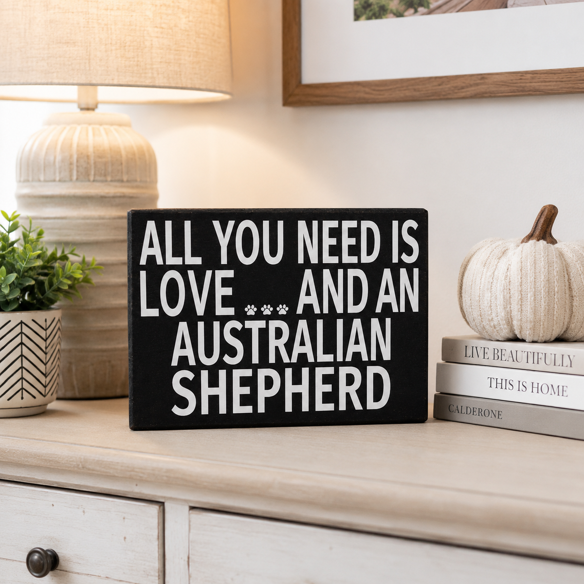 A black rectangular decorative sign with white text reading 'ALL YOU NEED IS LOVE .
