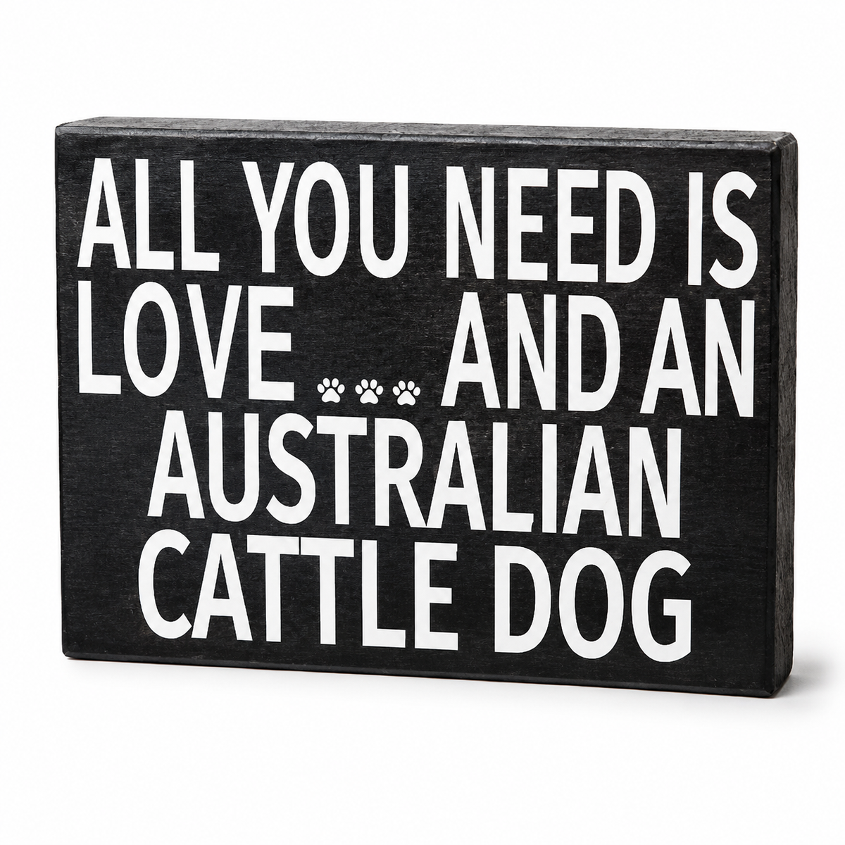 A rectangular black wooden sign with bold white text reading 'ALL YOU NEED IS LOVE.