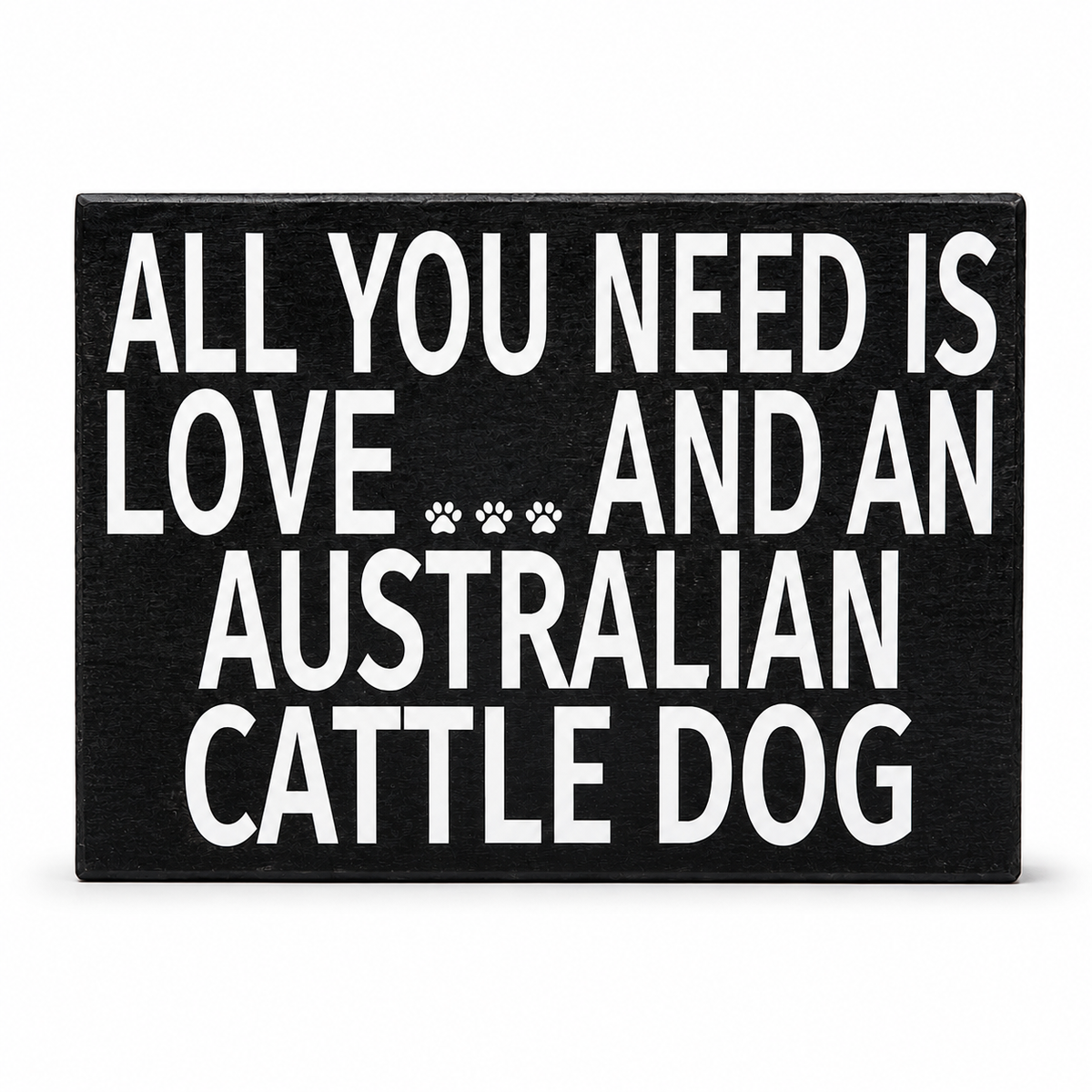 A rectangular black sign with bold white text reading 'ALL YOU NEED IS LOVE.