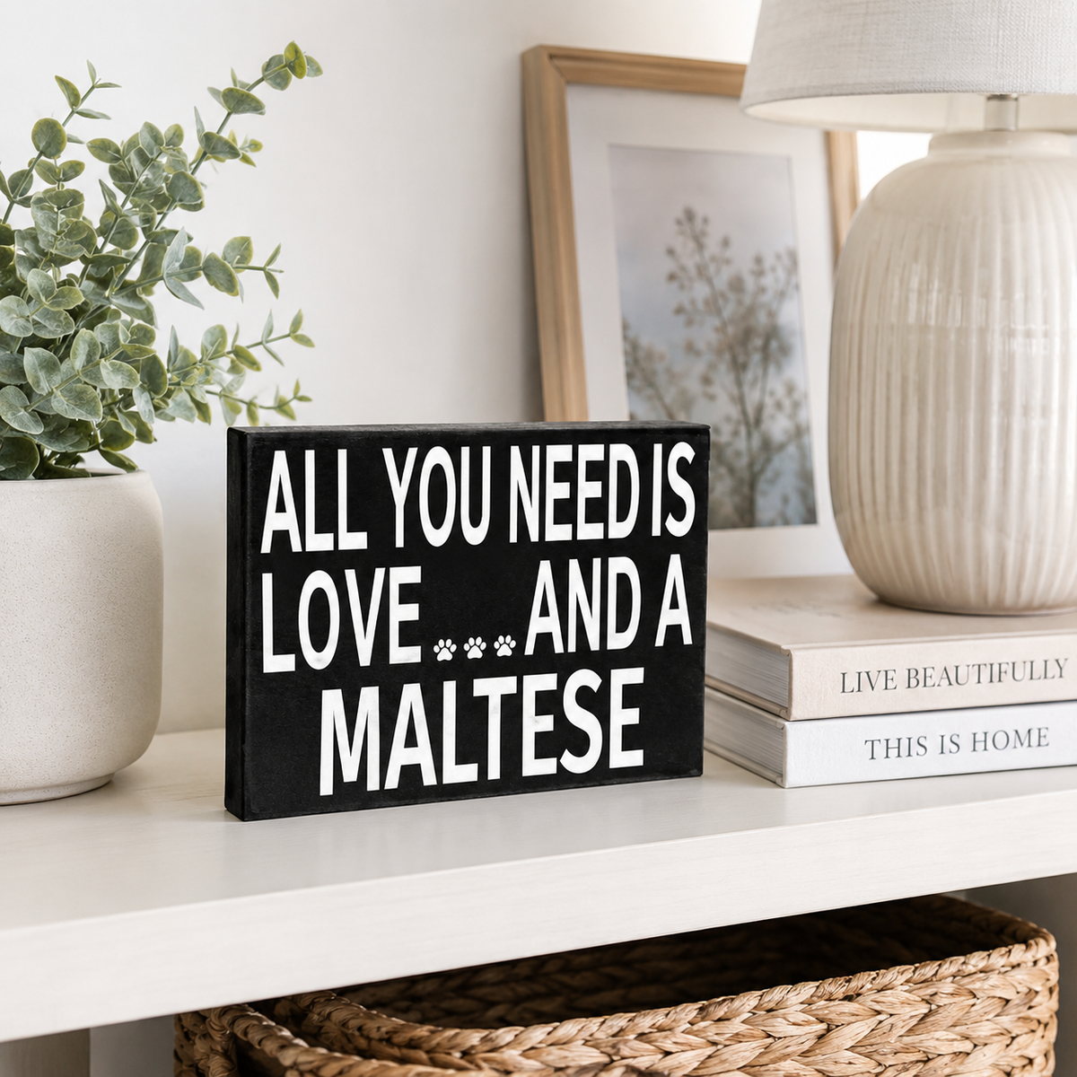 A black rectangular decorative sign with bold white text reading 'ALL YOU NEED IS LOVE.