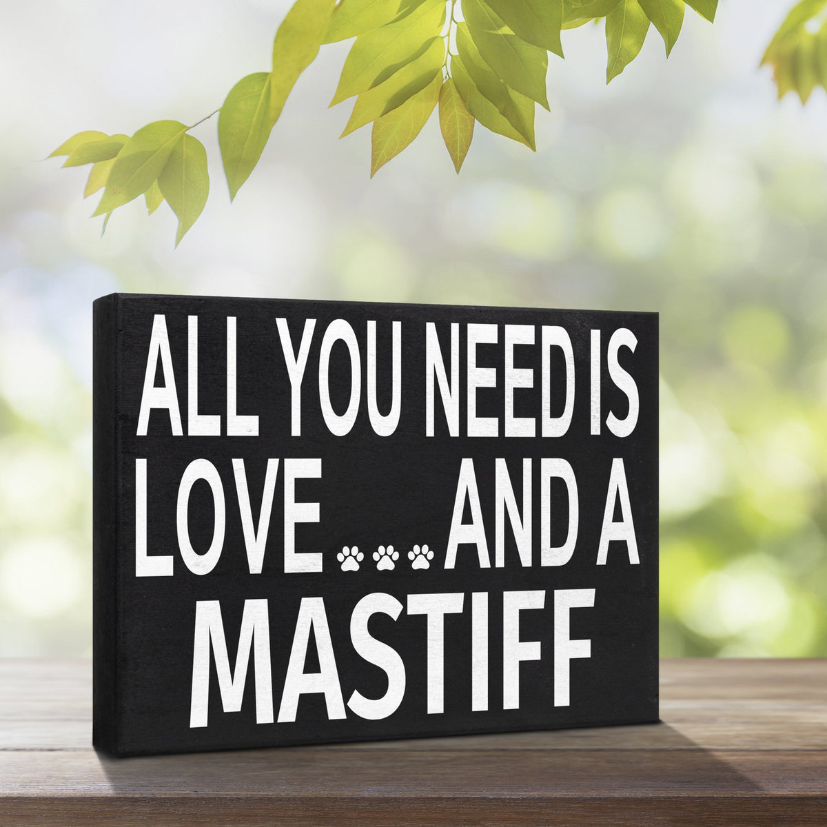 A black rectangular decorative sign with bold white text reading 'ALL YOU NEED IS LOVE.