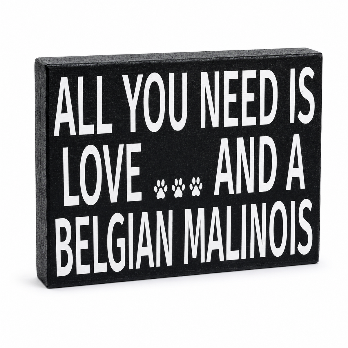 A rectangular black decorative sign with bold white text reading 'ALL YOU NEED IS LOVE.