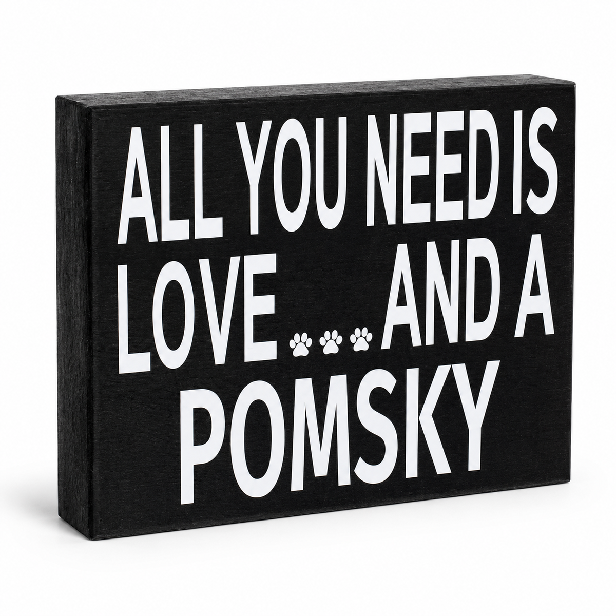 A rectangular black decorative sign with bold white text reading 'ALL YOU NEED IS LOVE.