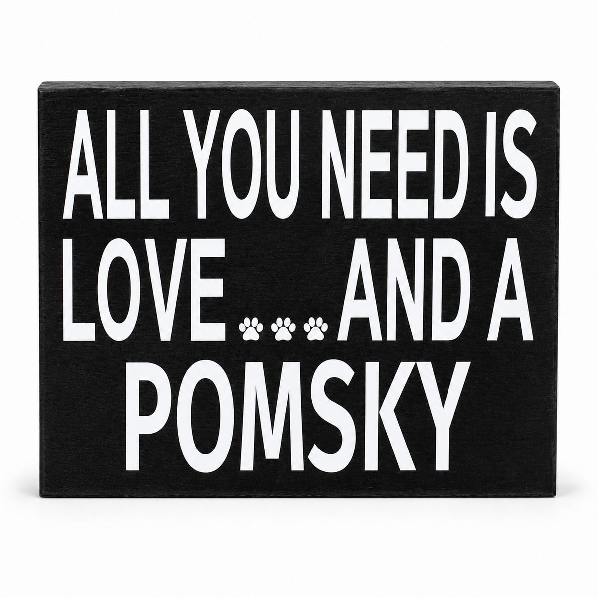 A rectangular black wooden sign with bold white text reading 'ALL YOU NEED IS LOVE.
