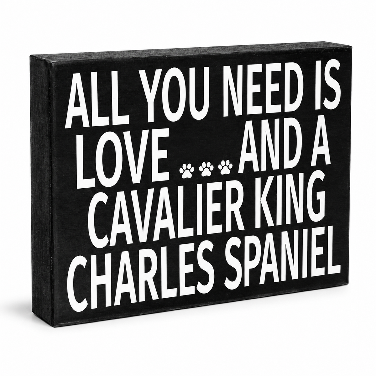 A rectangular black wooden sign with bold white text reading 'ALL YOU NEED IS LOVE.