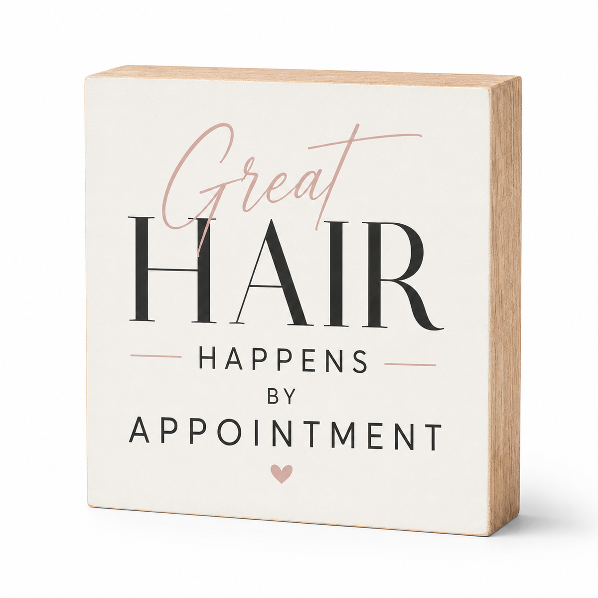 A square decorative wooden sign with a cream face and natural wood sides, printed with the phrase 'Great HAIR HAPPENS BY APPOINTMENT' in black and blush pink lettering, shown on a white background.