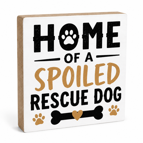 A square decorative wooden sign with a white front and natural kraft wood sides. The sign features the text 'HOME OF A SPOILED RESCUE DOG' in black and tan lettering, with paw prints and a bone graphic.