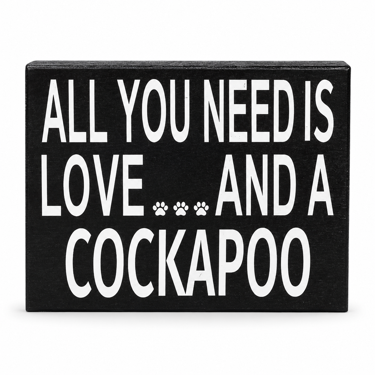 A rectangular black decorative sign with bold white text reading 'ALL YOU NEED IS LOVE.