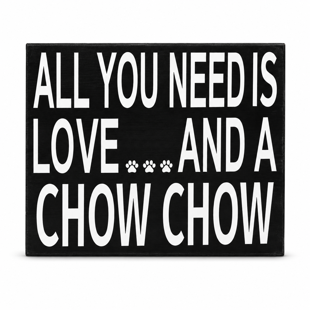 A rectangular black decorative sign with bold white text reading 'ALL YOU NEED IS LOVE.
