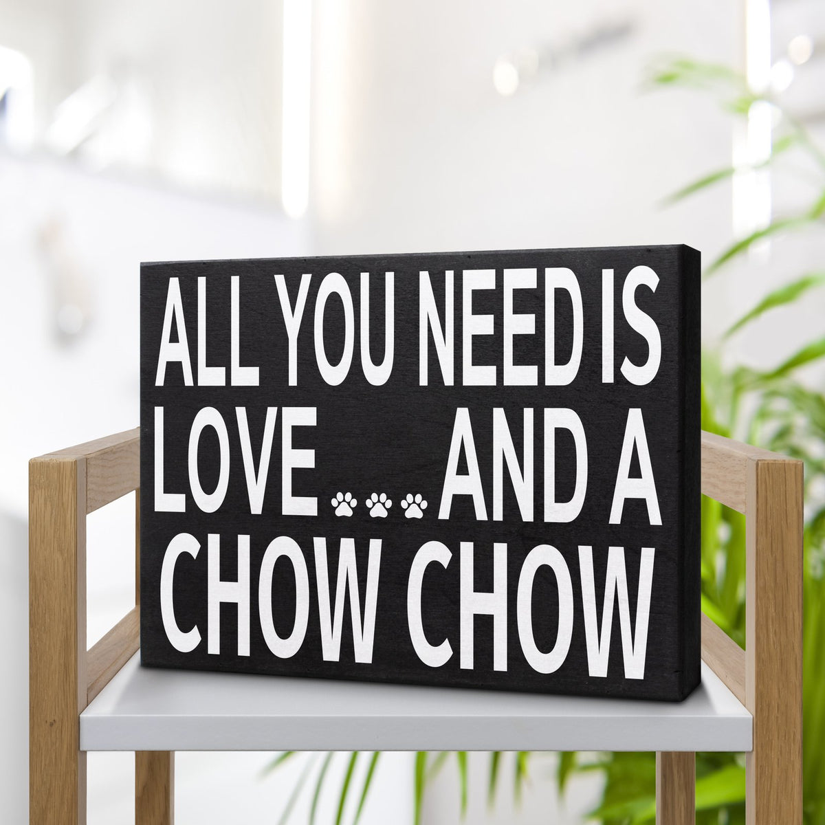 A rectangular black sign with bold white text reading 'ALL YOU NEED IS LOVE.