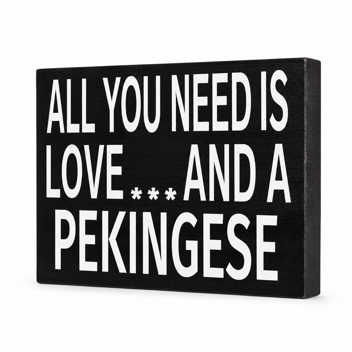 A rectangular black decorative sign with bold white text reading 'ALL YOU NEED IS LOVE.