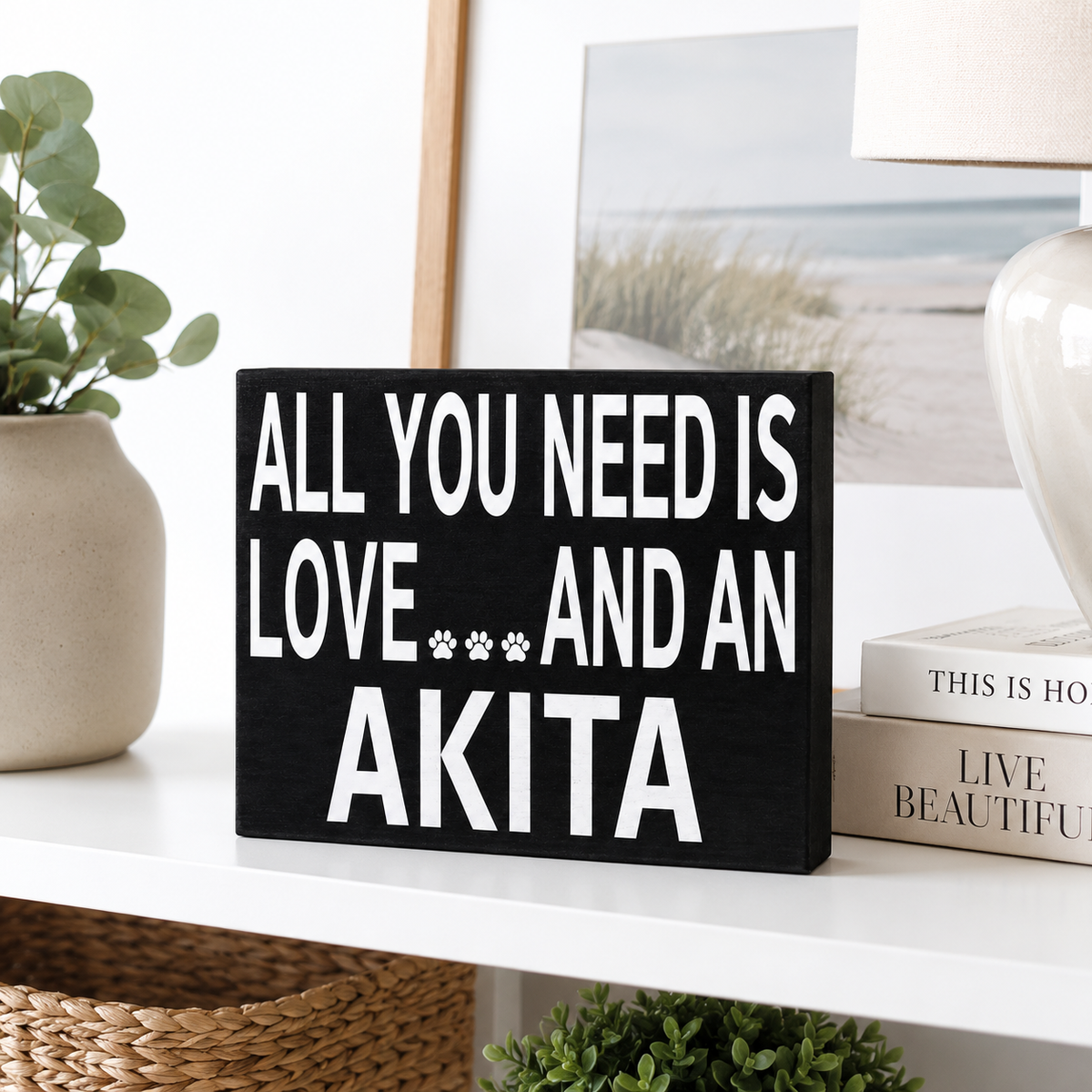 A black rectangular decorative sign with bold white text reading 'ALL YOU NEED IS LOVE.