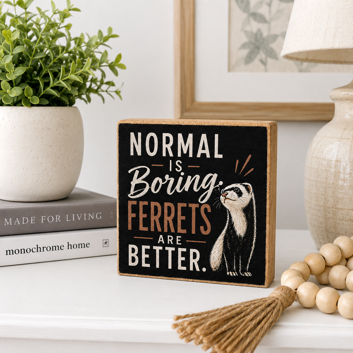 A square wooden sign with a black face and natural wood border displays the text 'NORMAL IS Boring. FERRETS ARE BETTER.
