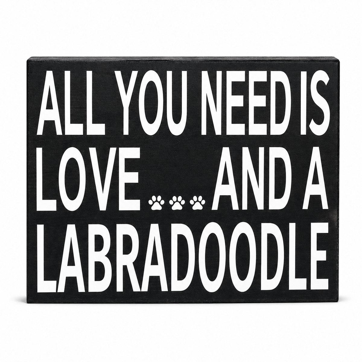 A rectangular black sign with bold white text reading 'ALL YOU NEED IS LOVE.