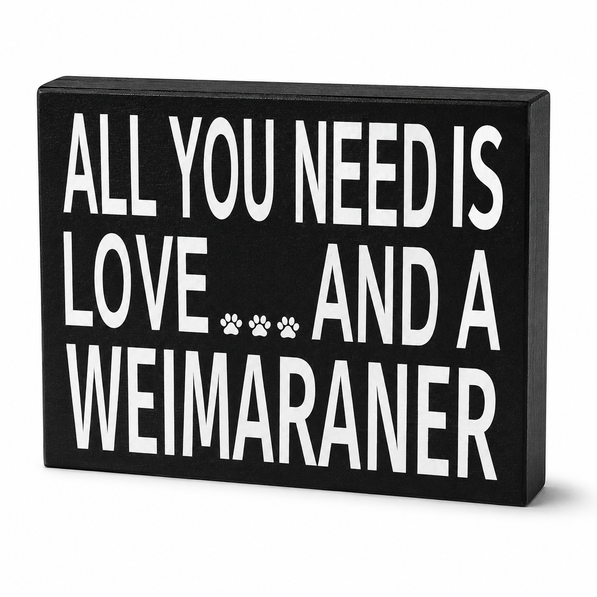 A rectangular black decorative sign with bold white text reading 'ALL YOU NEED IS LOVE.