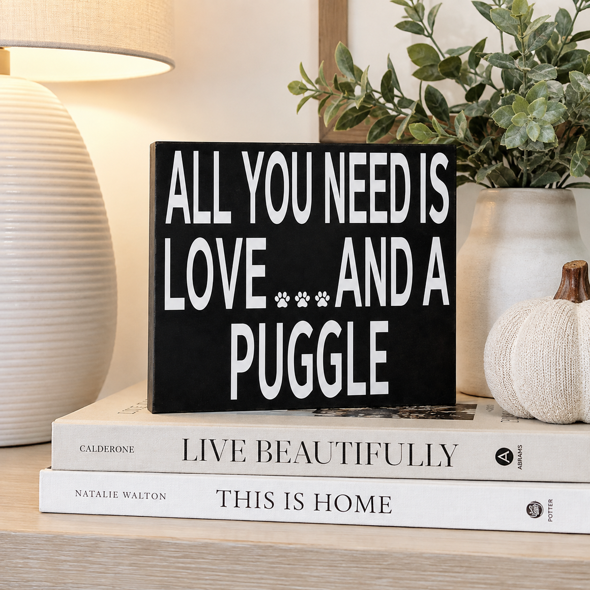 A black rectangular decorative sign with bold white text reading 'ALL YOU NEED IS LOVE.