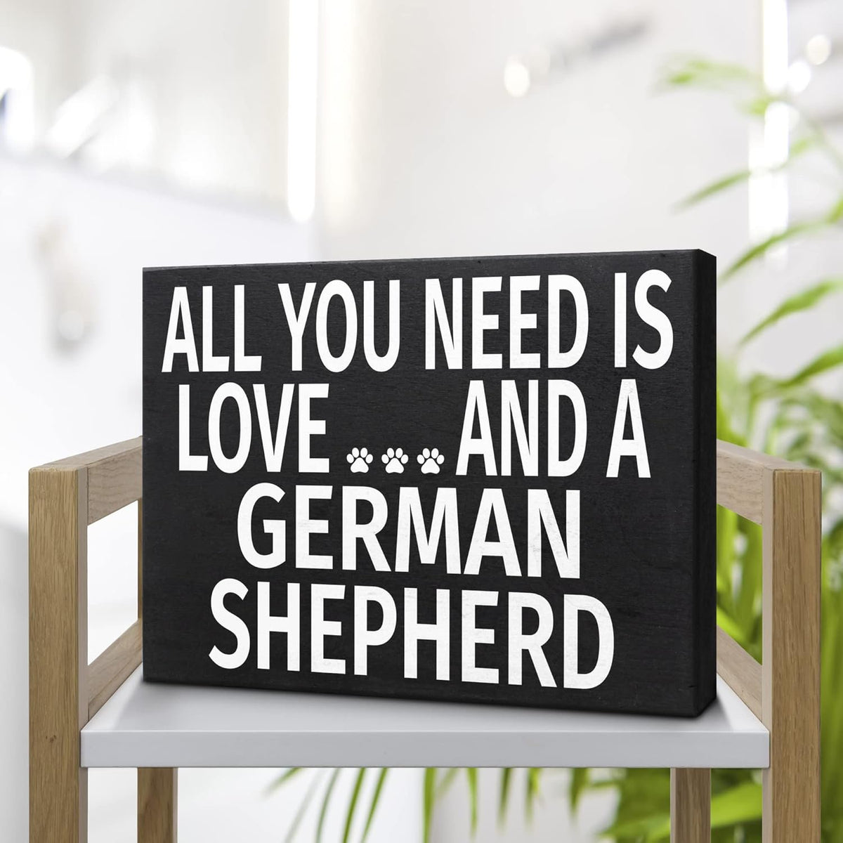 A rectangular black sign with bold white text reading 'ALL YOU NEED IS LOVE.