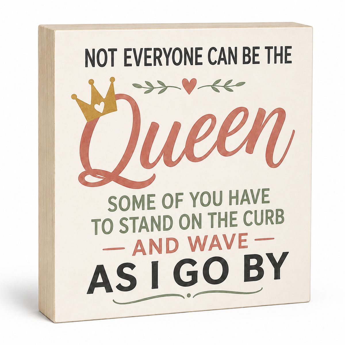A square decorative sign with a light wood edge and cream face, printed with the phrase 'NOT EVERYONE CAN BE THE Queen SOME OF YOU HAVE TO STAND ON THE CURB AND WAVE AS I GO BY' in black, dusty pink, and sage green lettering, with a small gold crown and leaf motif.