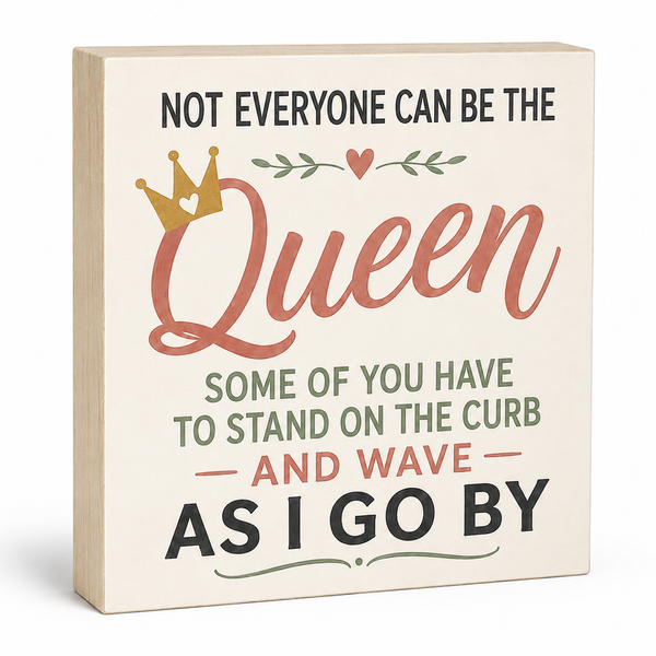 A square decorative sign with a light wood edge and cream face, printed with the phrase 'NOT EVERYONE CAN BE THE Queen SOME OF YOU HAVE TO STAND ON THE CURB AND WAVE AS I GO BY' in black, dusty pink, and sage green lettering, with a small gold crown and leaf motif.