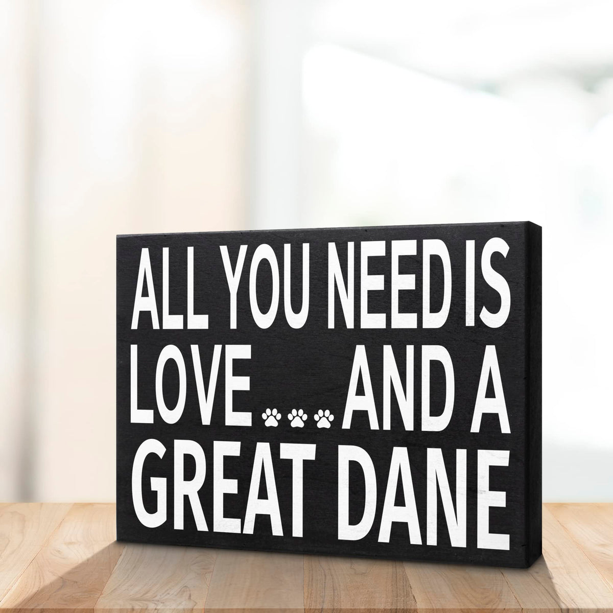 Decorative sign with text 'All you need is love and a great dane' on a wooden surface.