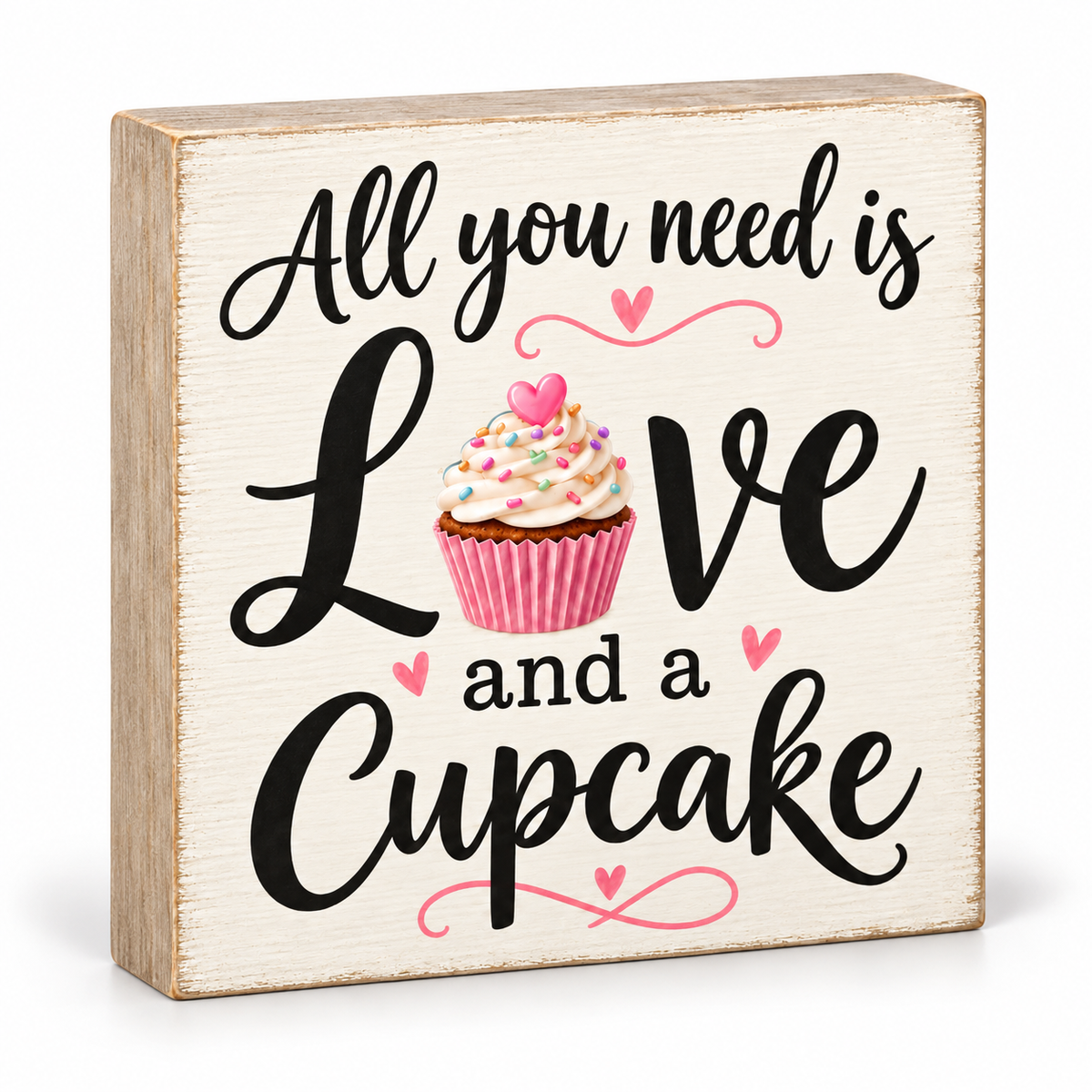 A square wooden sign with a distressed cream face and natural wood edges, featuring the phrase 'All you need is Love and a Cupcake' in black script, with a pink cupcake illustration in the center.