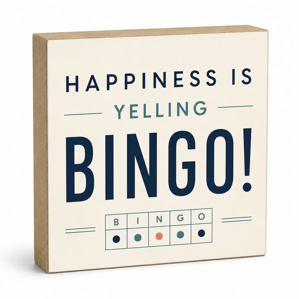 A square decorative sign with a kraft-paper side edge and a cream face printed with the phrase “HAPPINESS IS YELLING BINGO!” in navy and muted blue lettering, plus a small bingo grid at the bottom.