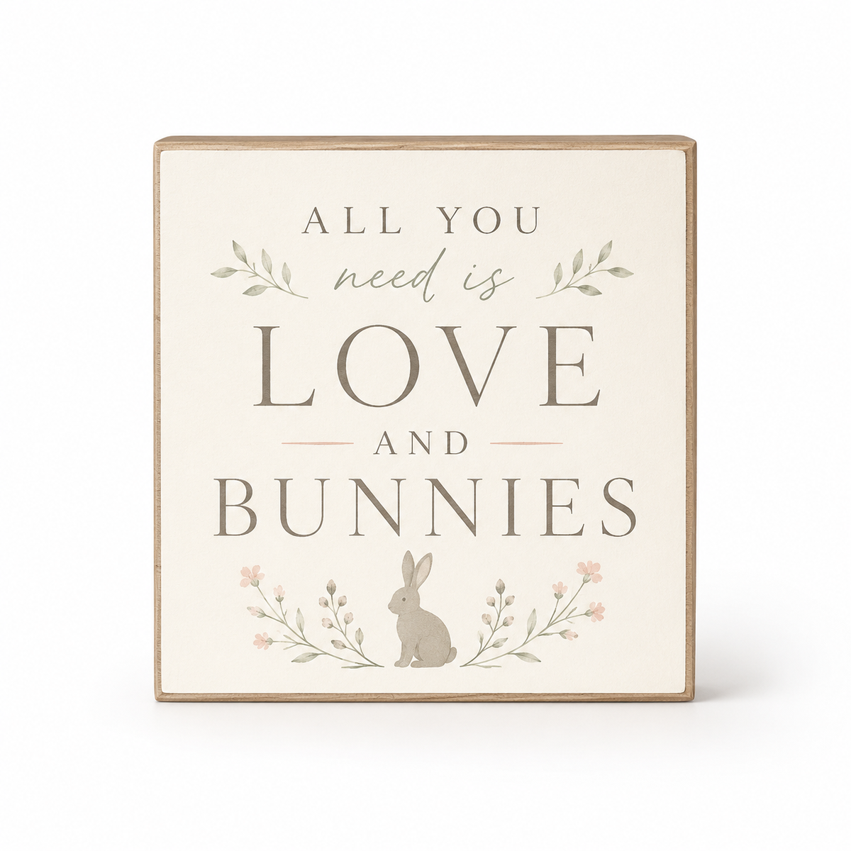 A square decorative wooden sign with a light beige face and natural wood border, featuring the phrase 'ALL YOU need is LOVE AND BUNNIES' in gray lettering, with a small bunny and floral illustrations.