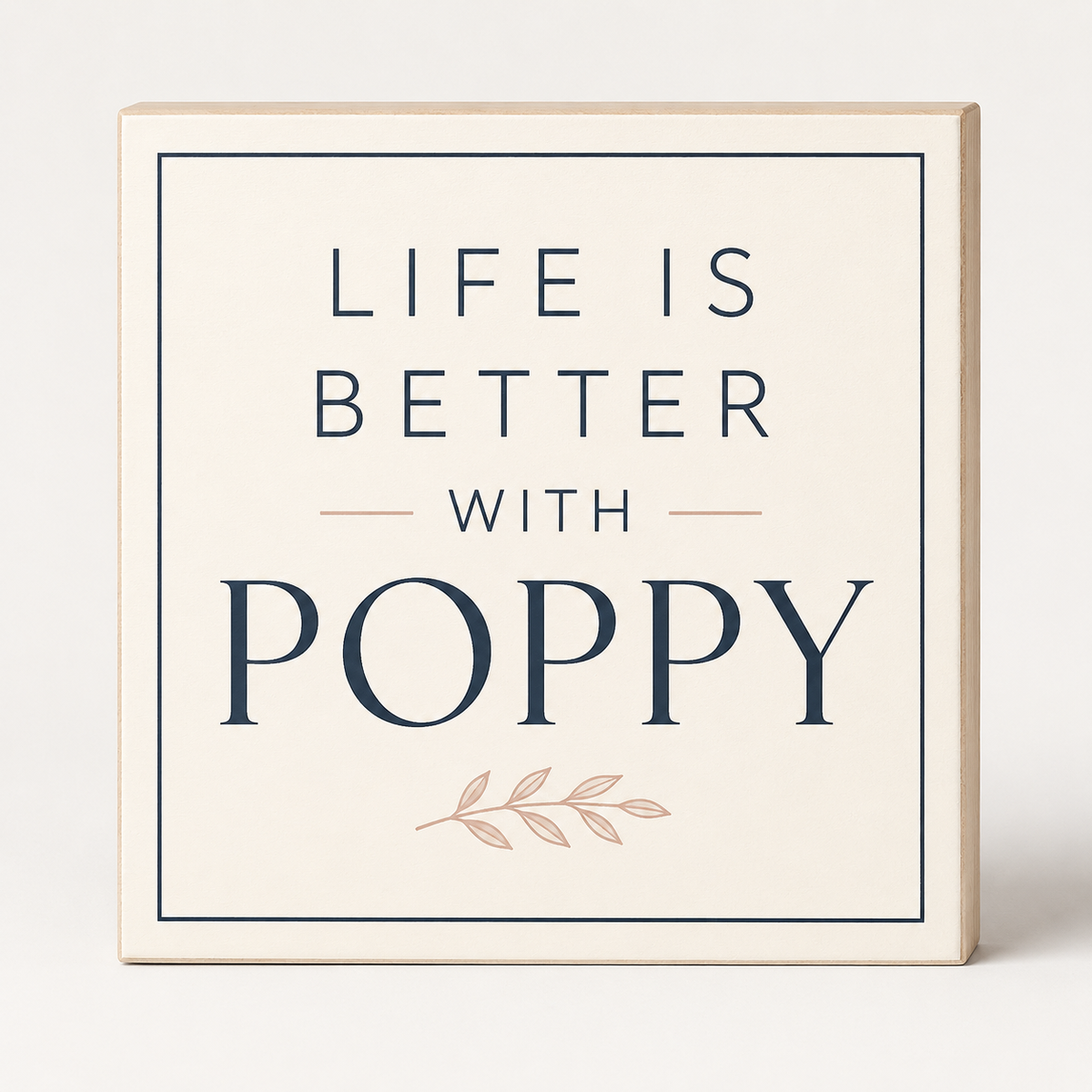 A square decorative sign with a light wood border and cream face that reads “LIFE IS BETTER WITH POPPY” in dark navy lettering, with a small blush pink leaf motif below, shown on a clean light background.